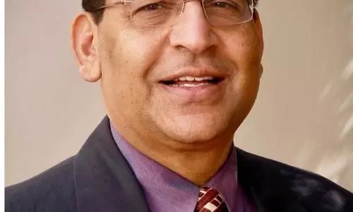 Portrait of an elderly Indian male doctor in formal attire, photographed indoors, representing a senior medical professional.