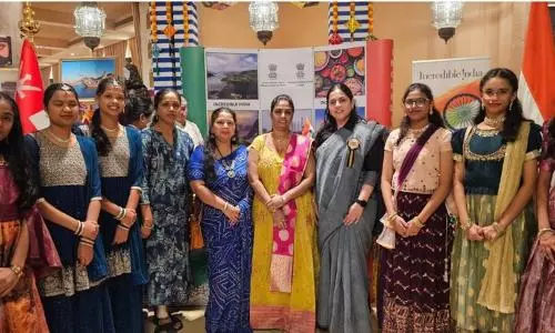 Indian women and young performers stand in traditional attire at the Indian Pavilion during the “A Cup for a Good Cause” charity event in Jeddah, with Incredible India displays in the background.