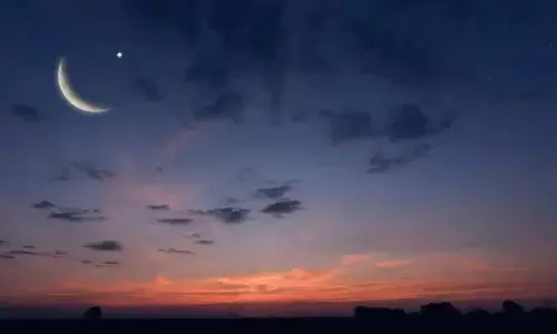 A thin crescent moon visible in the evening sky, marking the beginning of Ramadan.