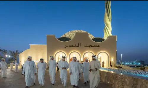 Sheikh Sultan bin Ahmed Al Qasimi and officials walk outside Al Nasr Mosque in Al Dhaid at dusk, with the illuminated dome and minaret visible behind them. Sheikh Sultan bin Ahmed Al Qasimi and officials walk outside Al Nasr Mosque in Al Dhaid at dusk, with the illuminated dome and minaret visible behind them.