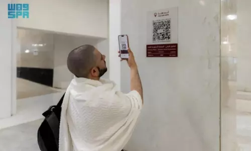 A pilgrim scans a QR code with his phone to access a smart interactive map inside the Grand Mosque in Makkah.