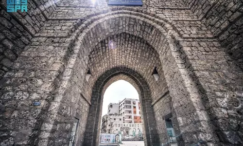 The historic stone archway of Bab Makkah in Jeddah’s old district, with modern buildings visible beyond the gate. The historic stone archway of Bab Makkah in Jeddah’s old district, with modern buildings visible beyond the gate.