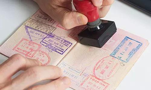 A passport being stamped with an entry visa by an immigration officer.