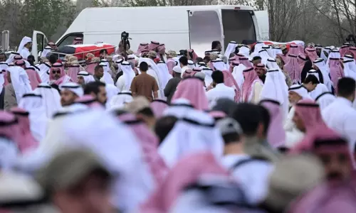 Crowds gather as the bodies of two Kuwaiti naval officers are carried during a funeral procession.
