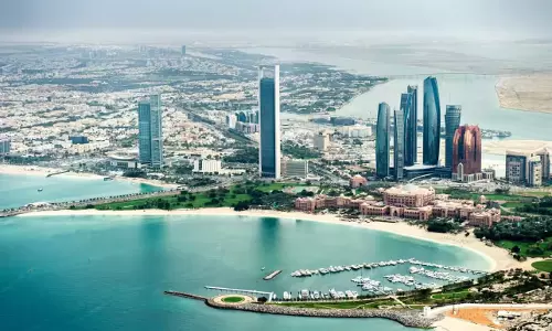 Aerial view of Abu Dhabi skyline and waterfront, including Etihad Towers and surrounding coastal areas.