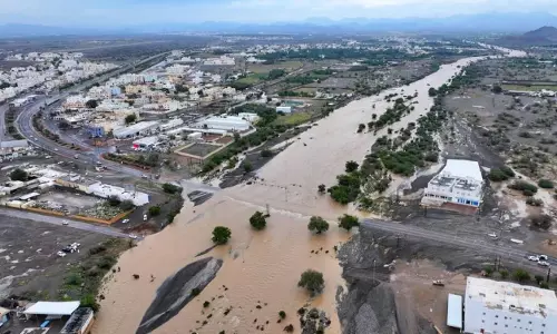 Aerial view of flooding in Oman showing swollen wadis overflowing into nearby roads and residential areas after heavy rainfall.