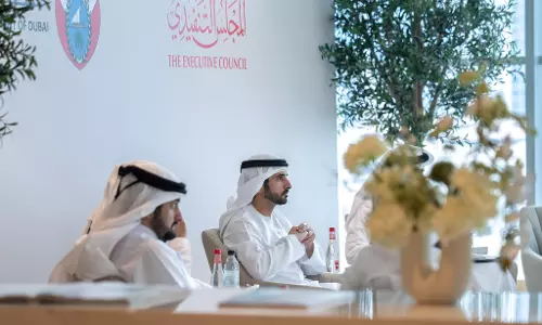 Officials seated at a meeting of Dubai’s Executive Council, with men in traditional Emirati attire listening during a session in a modern indoor setting.
